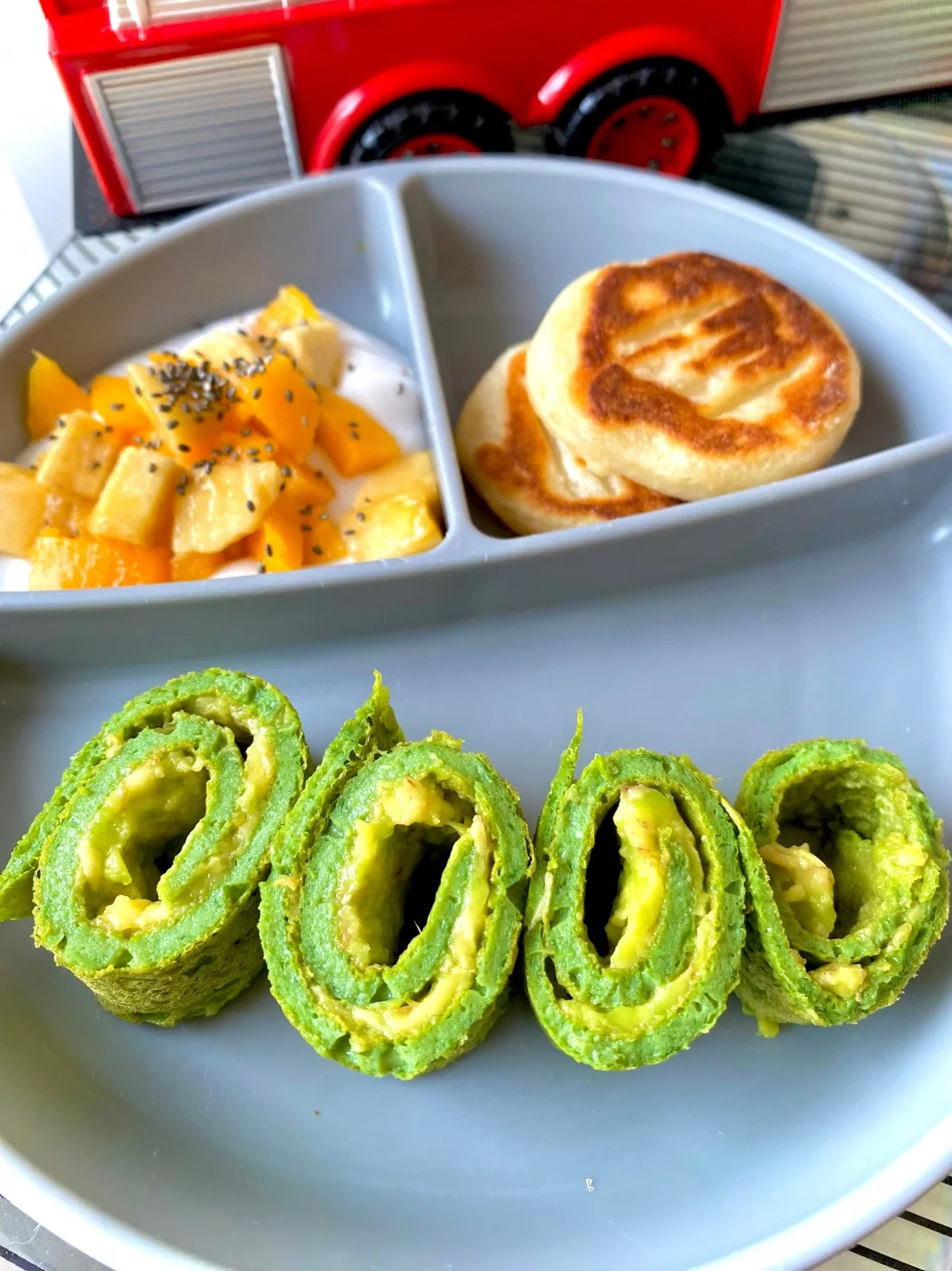 Plato con rollitos verdes de espinaca, tortitas y yogur con mango y chía.